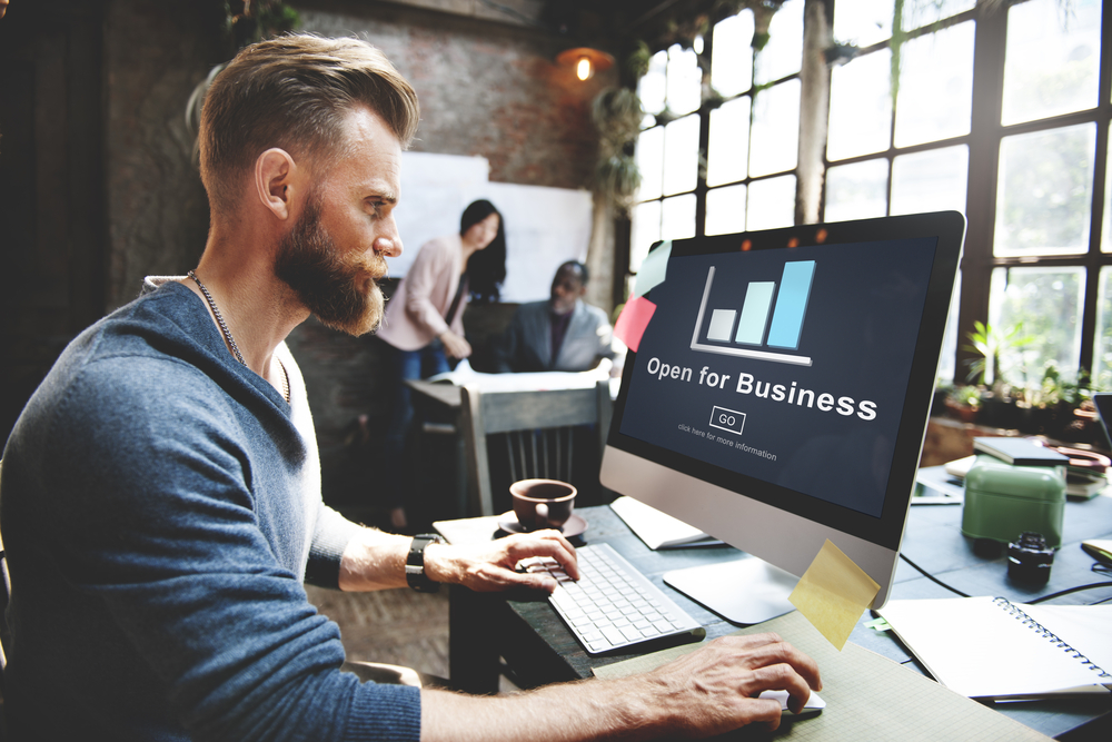 man working on his small business website while others work in the background