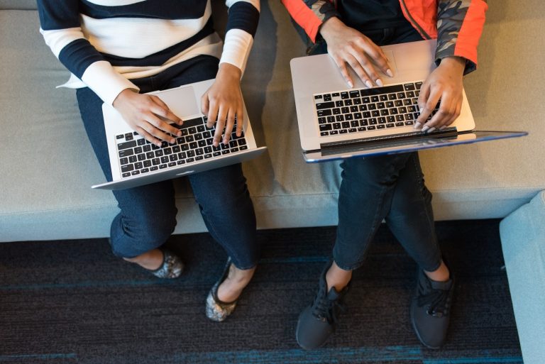two youngsters using macbook