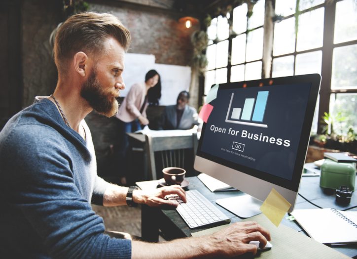 man working on his small business website while others work in the background