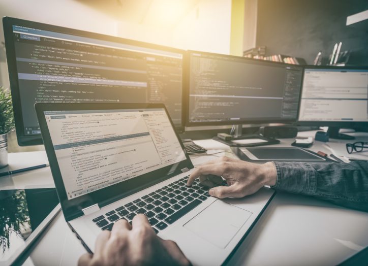 man coding a wordpress site on multiple monitors